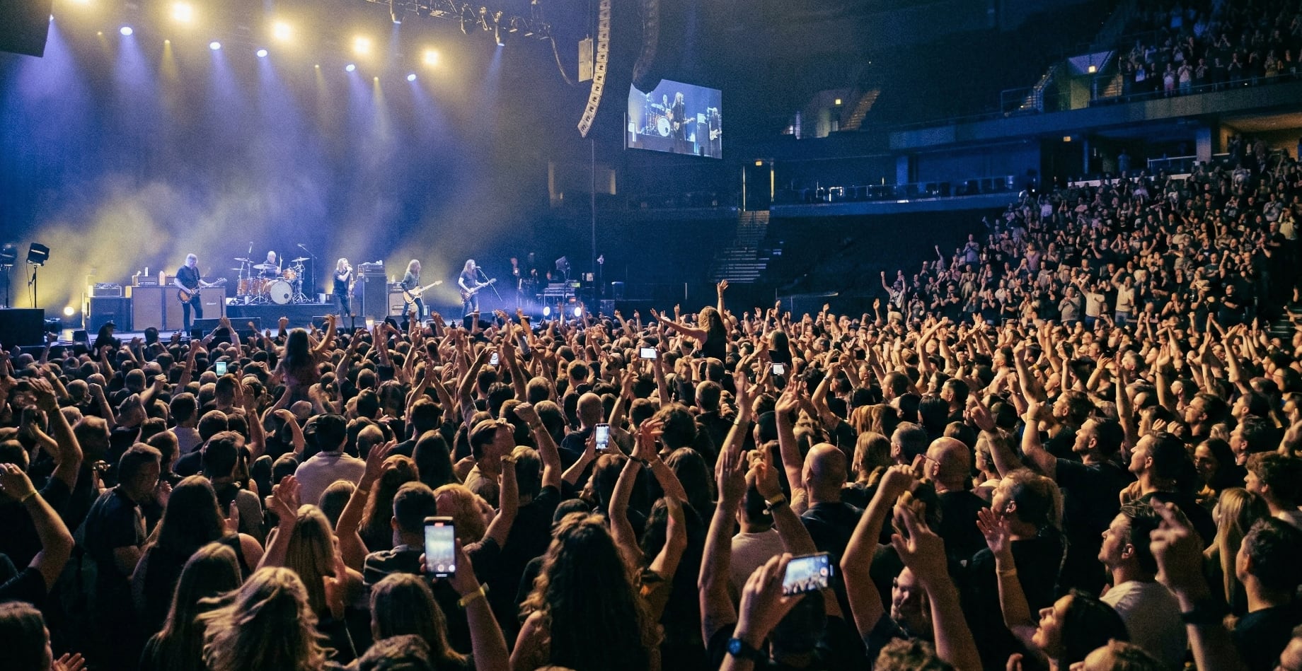 Concert crowd with raised hands and stage lighting