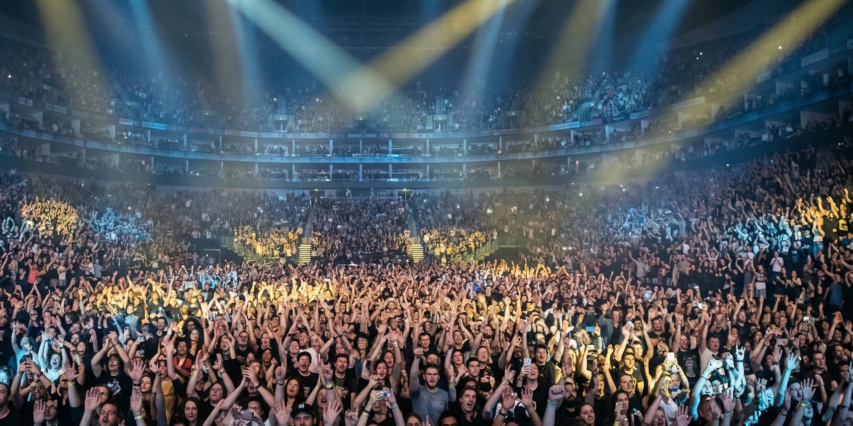 Concert crowd with raised hands and stage lighting